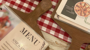 A menu card and paperwork on a restaurant table with a red and white check tablecloth.