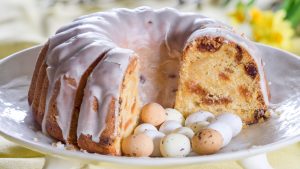 An iced fruit bundt cake on a white plare with Mini Eggs.