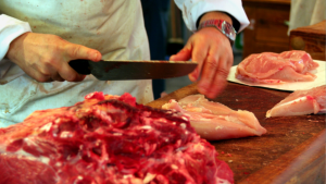 A butcher carving up fresh meat.