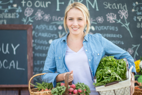 A young blonde woman carrying baskets of fresh produce for in alignment with her restaurant's hyperlocal menu strategy.