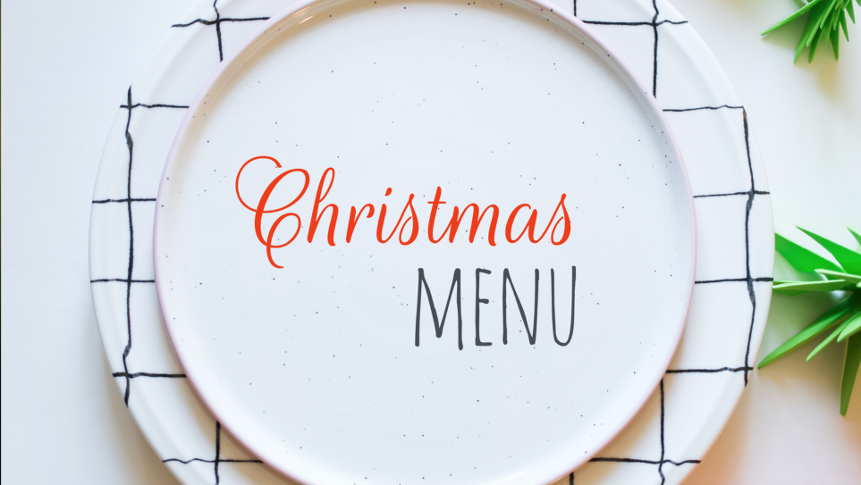 A white plate on a white table, decked with wintry foliage, with the words CHRISTMAS MENU